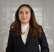 Girl with long brown hair wearing a black suit and white shirt. 