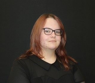 Woman with black top and medium length red hair. 