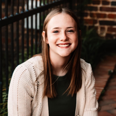 Woman with a black top and tan cardigan and long blond hair. 