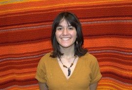 Women with burnt orange top and medium length brown hair. 