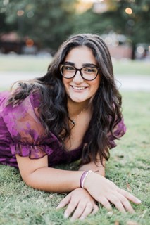 Woman with purple top and long brown hair. 