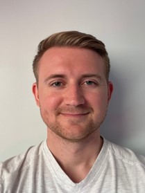 Man with white top and short blond hair. 